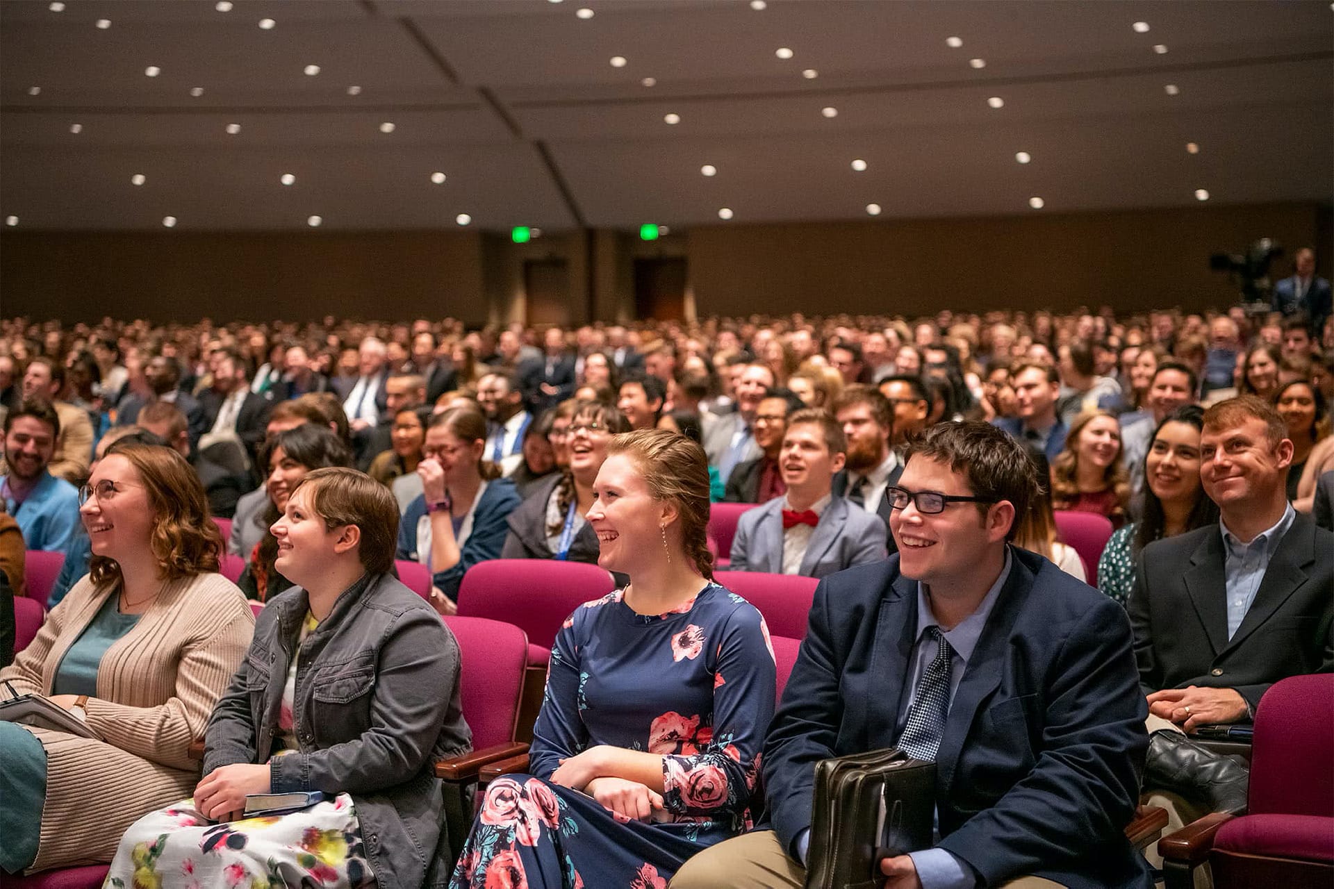 Students sitting in the PCC Crowne Centre and smiling while listening to preaching.