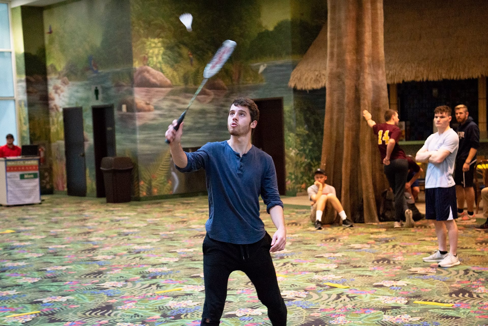 Male student lifting his racket while playing badminton.