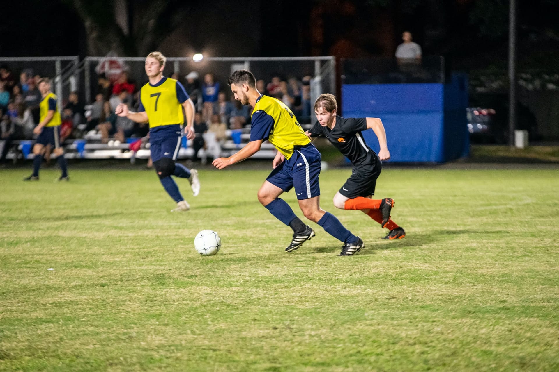Men's collegian soccer players running after the ball. 