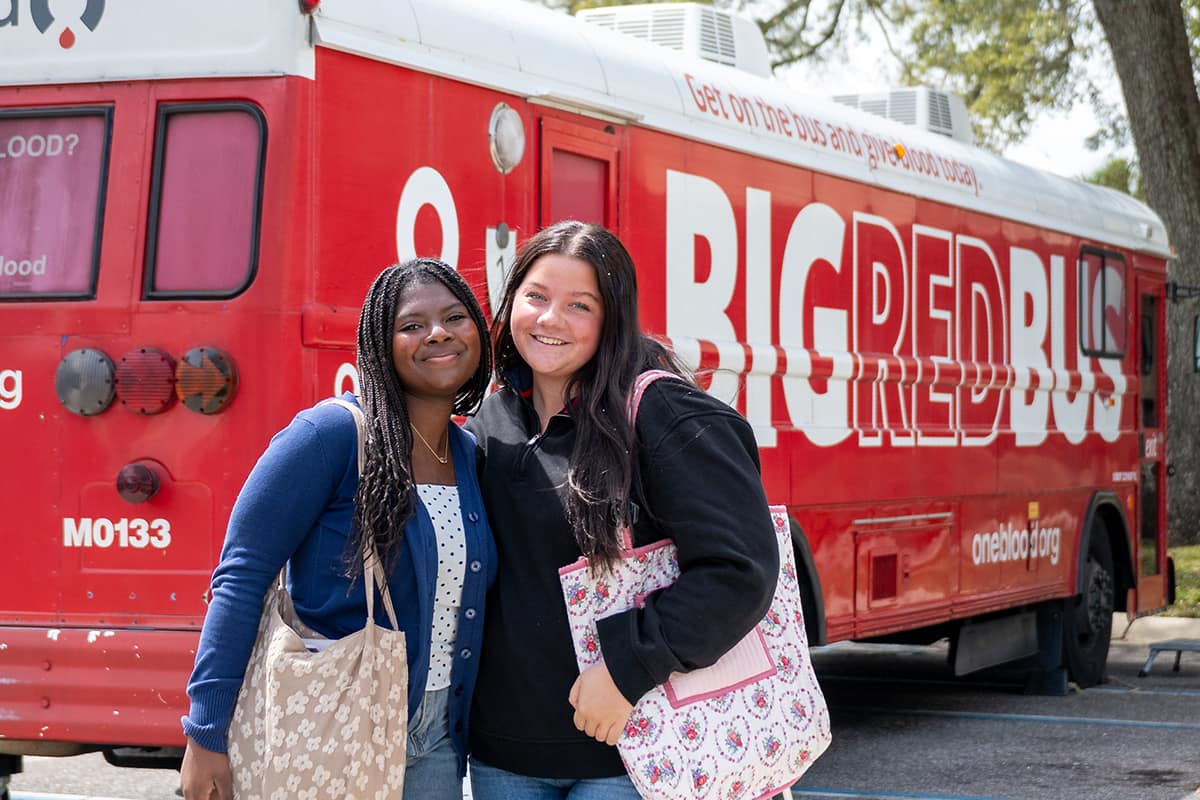 Friends pose in front of the blood donation bus