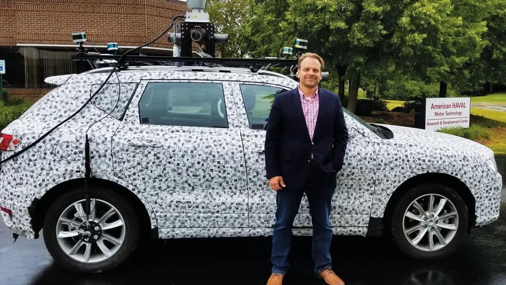 Shane Elwart standing in front of a car.