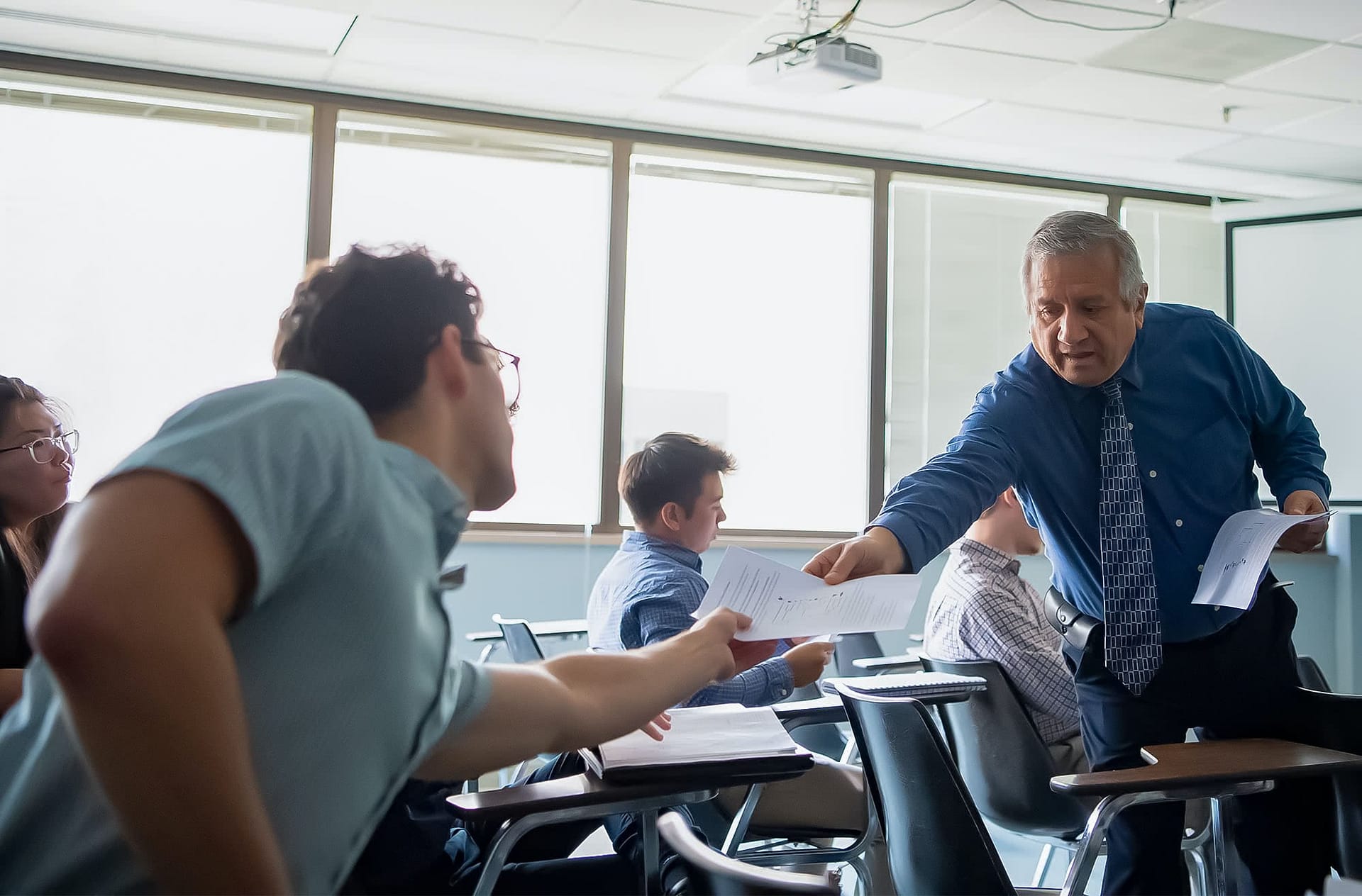 Male graduate student reaching out toward a paper in the professor's hand.