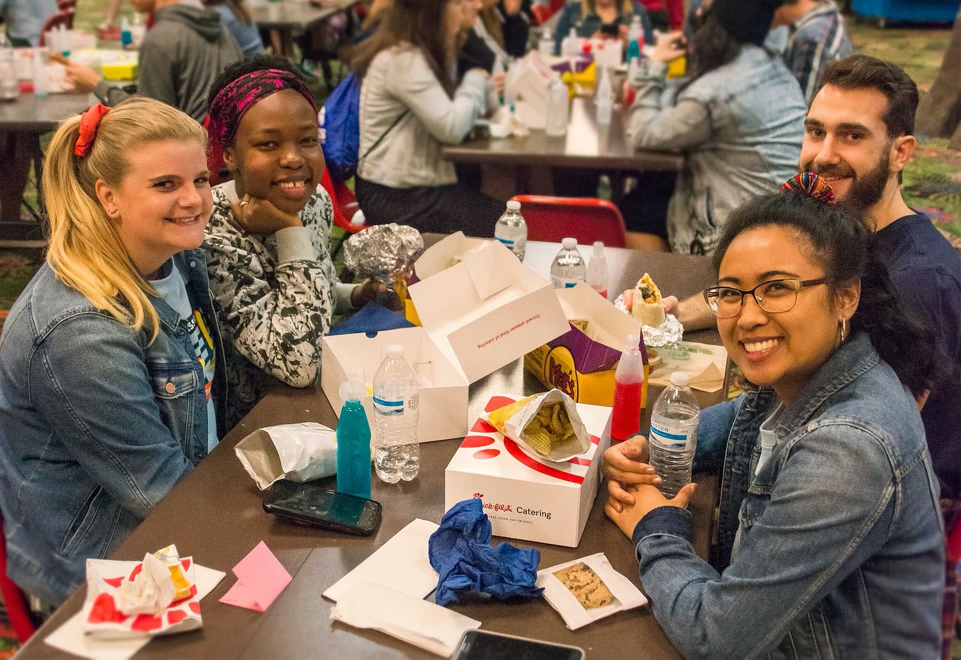 Four students sitting and eating together at their senior class party..