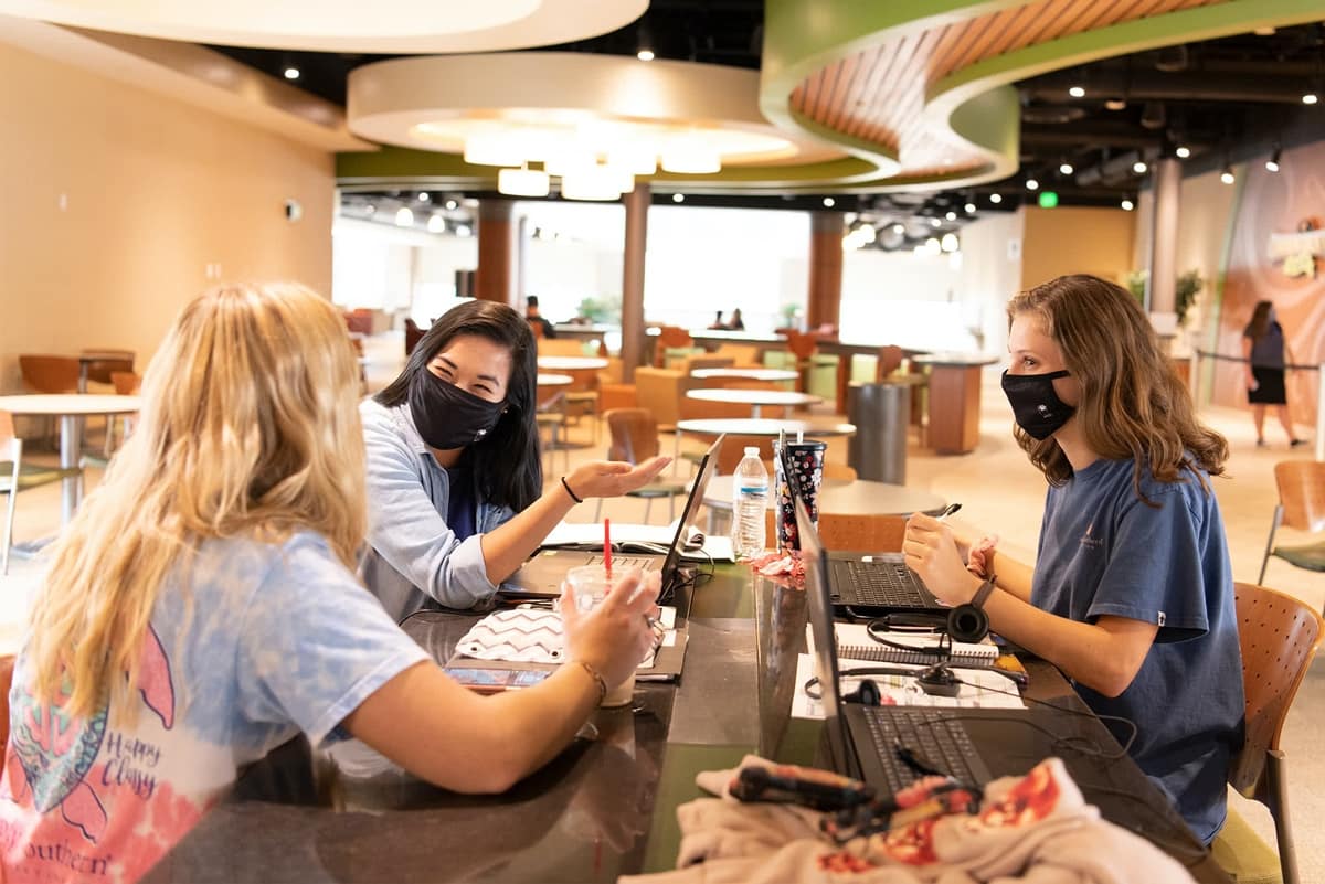 Three PCC girls wearing masks while studying in the commons