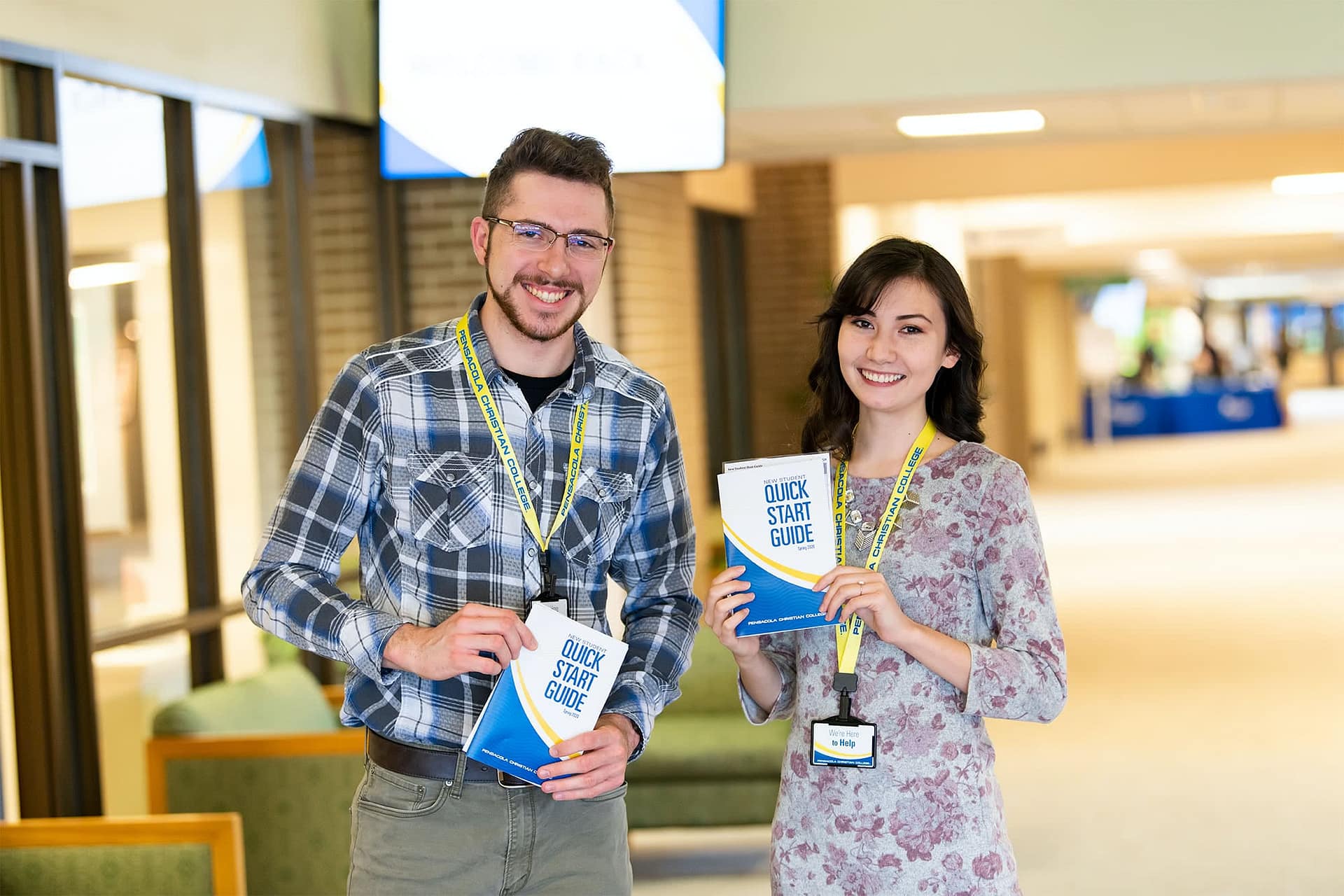 Welcome volunteers smiling and holding quick start guides.