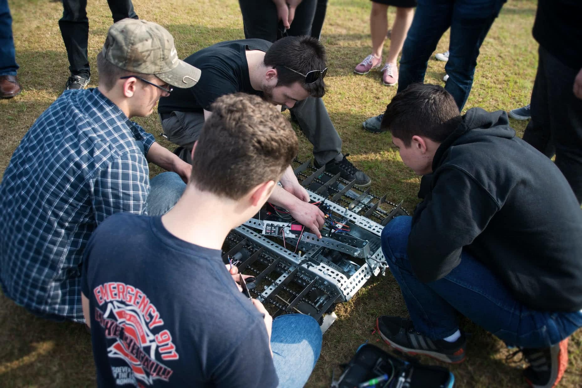 Four male students looking a and working on their team's robot for the Engineering Design Contest.
