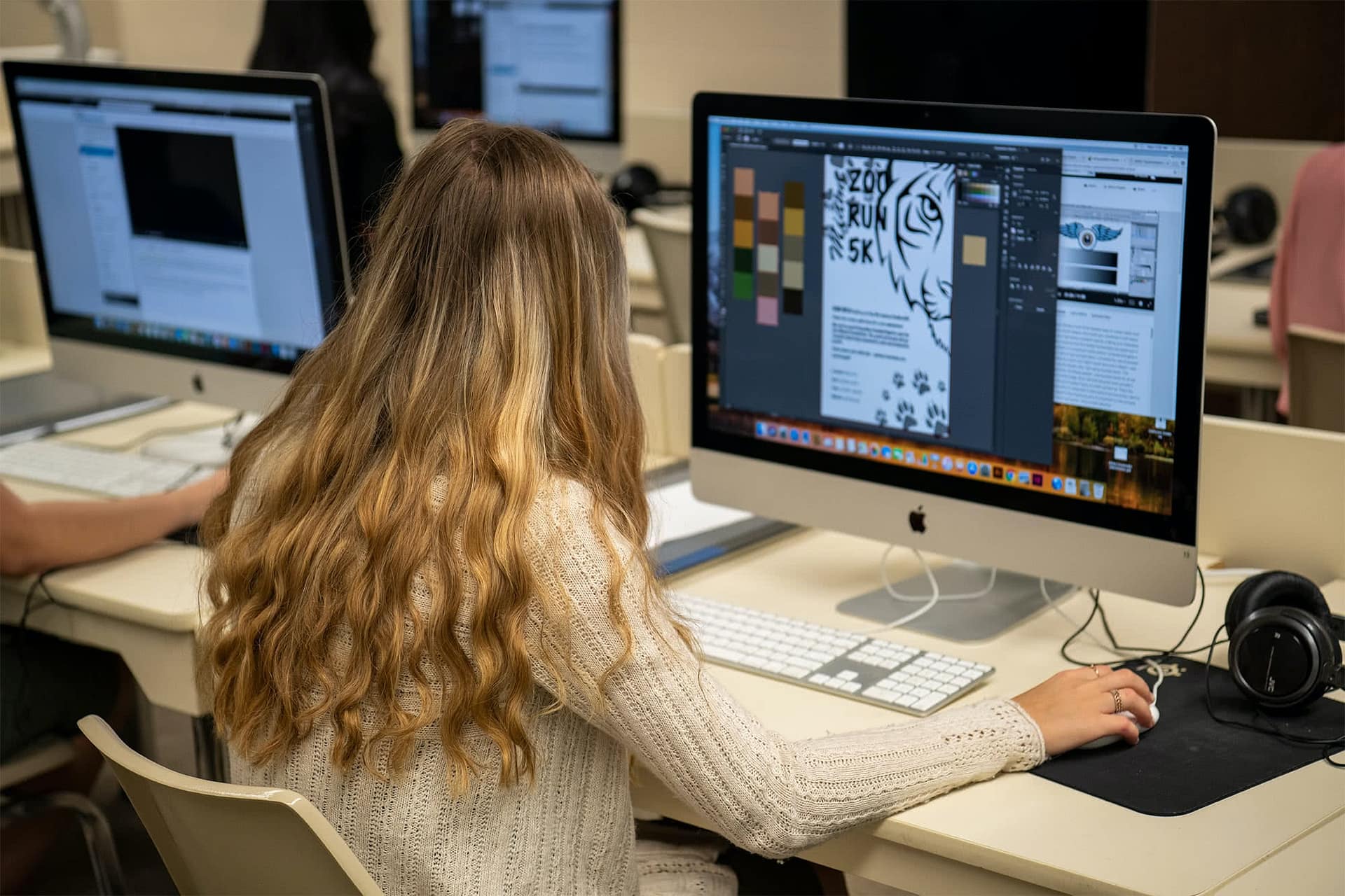 A Visual Arts student works on a poster for a zoo's 5K in her graphic design class.