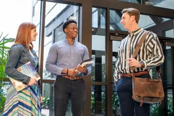 three graduate students greet each other