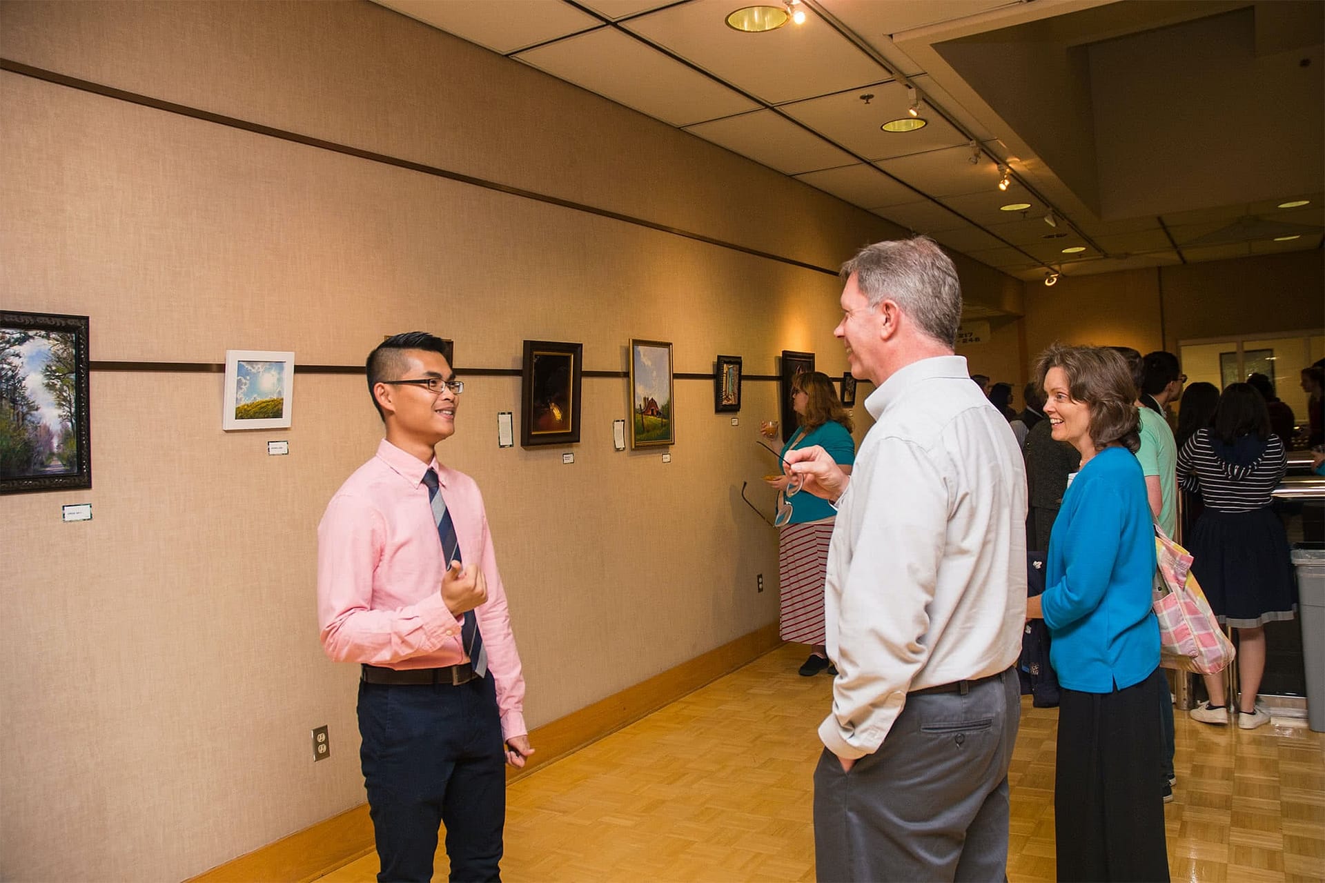 Visual Arts student talks with a visitor about his art pieces.