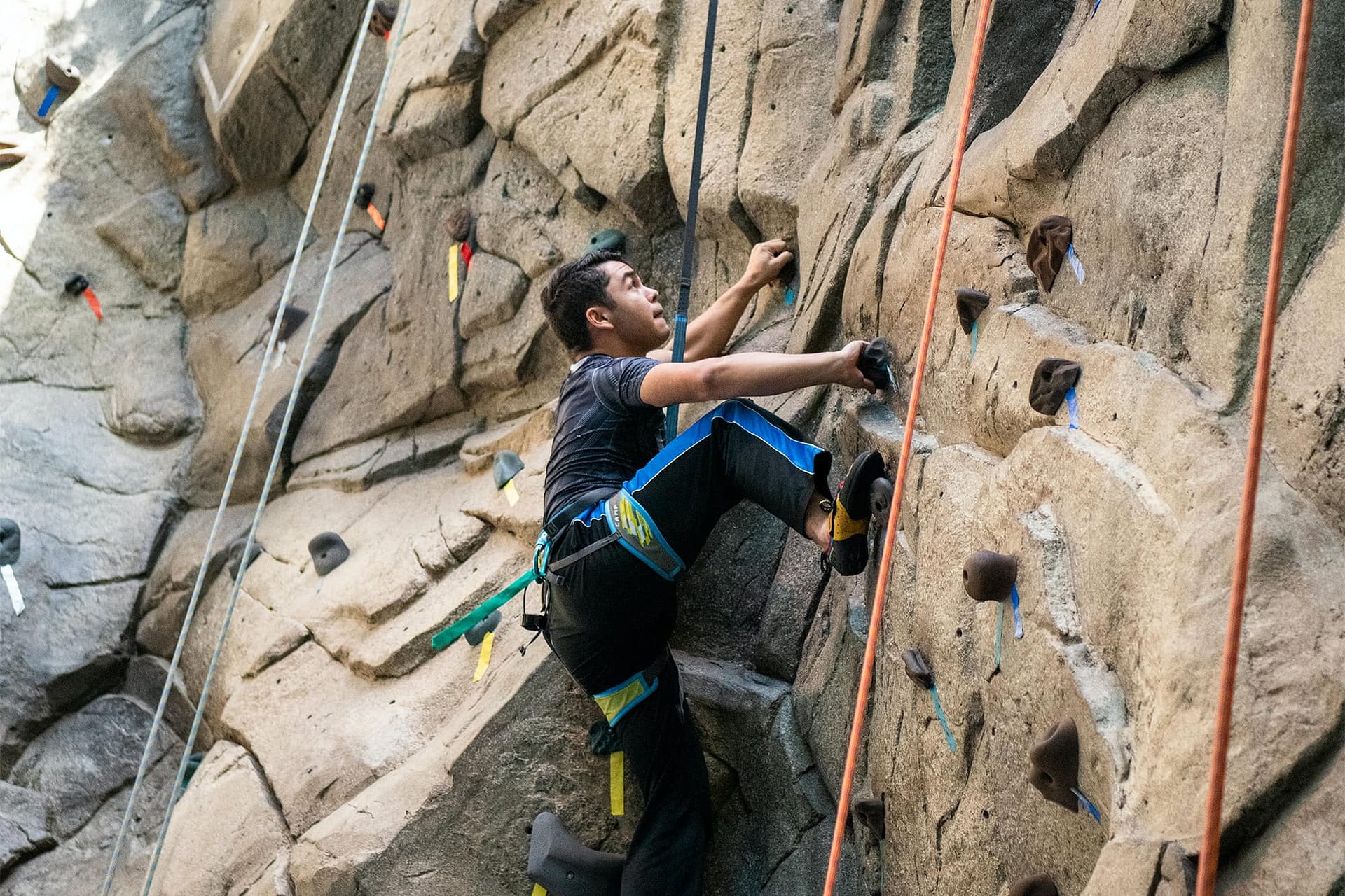 Male student climbing the Sports Center rock wall.
