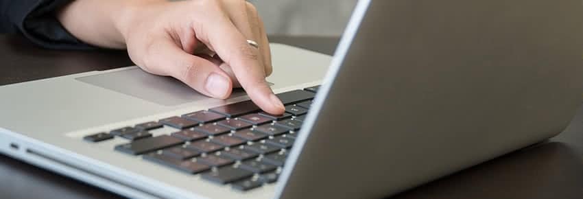 Hand pressing a key on a laptop