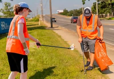 Two students pick up trash along a highway