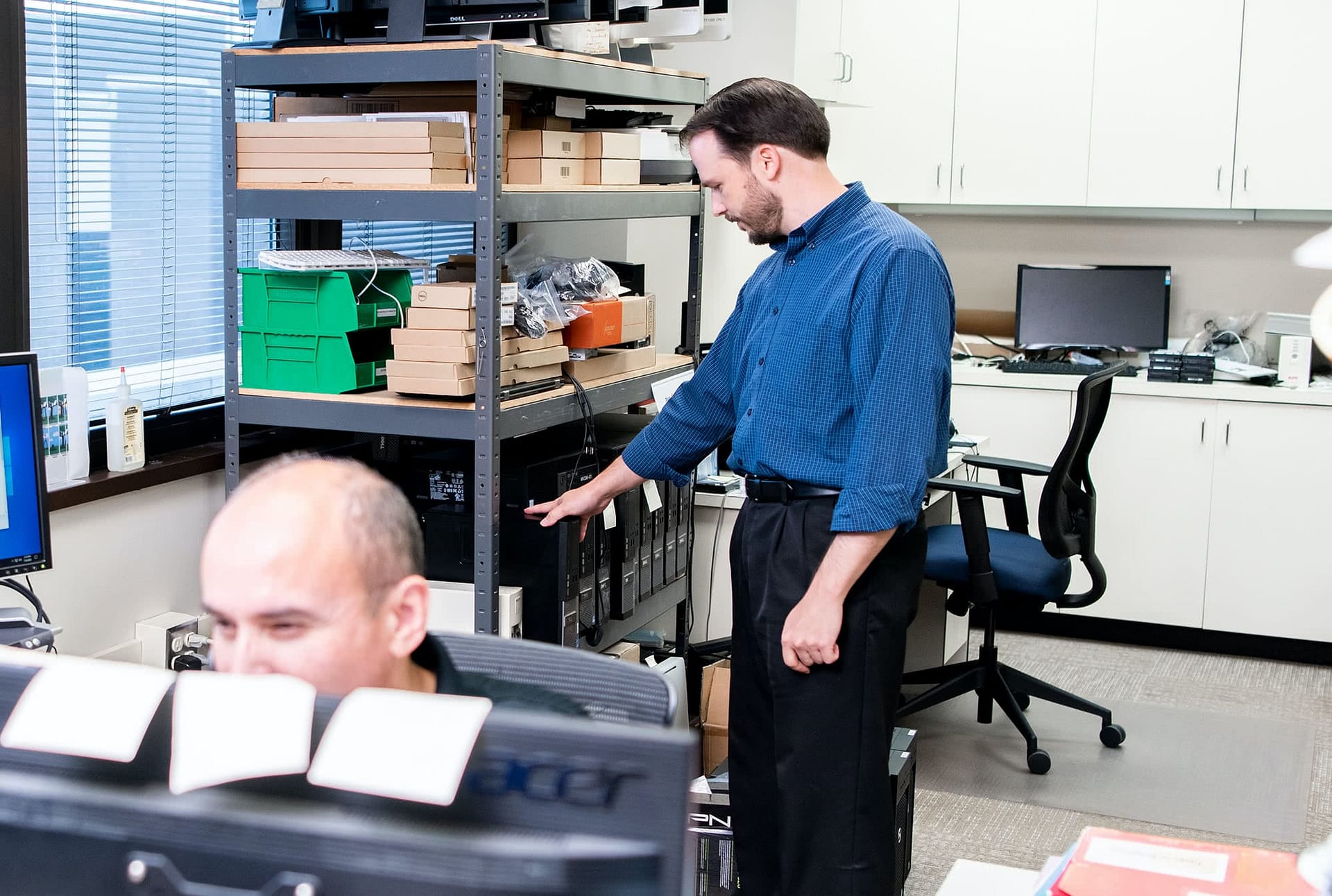 System Administrator Wayne Siegler looks at router in IT office.