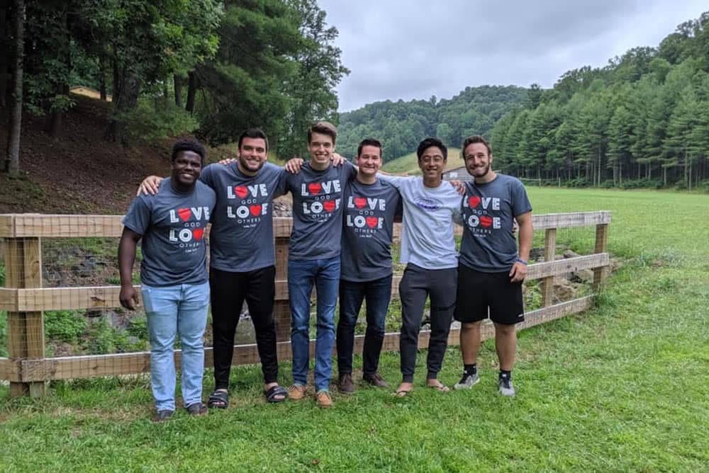 Male students standing together with their arms around each other's shoulders. 