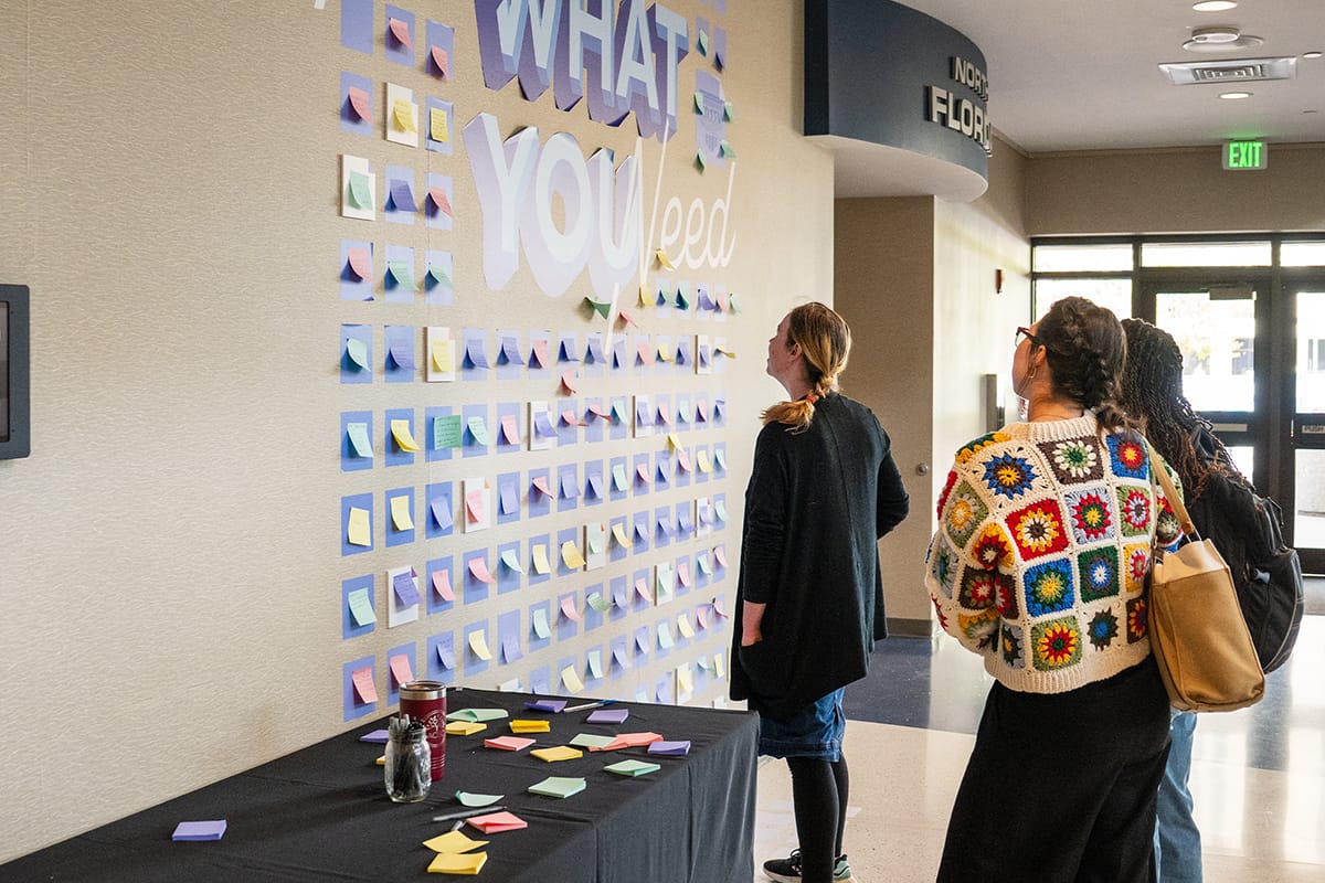 Students reading the encouragement from the "Take what you need" wall
