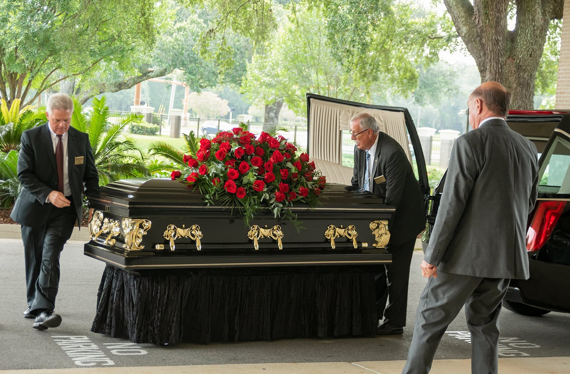 Funeral home staff members moving the casket to the hearse.