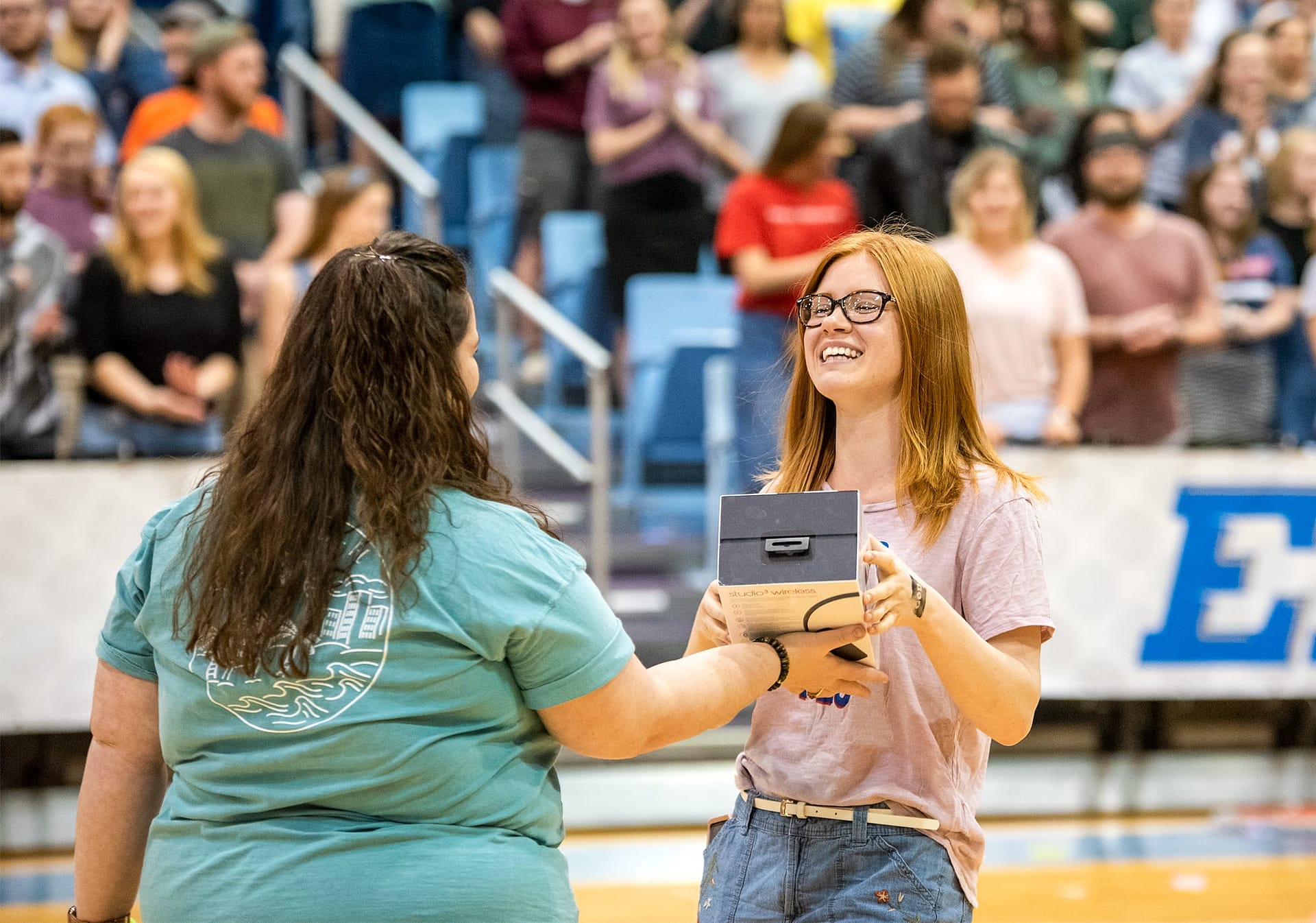 Female PCC student smiling as she is being handed a prize.