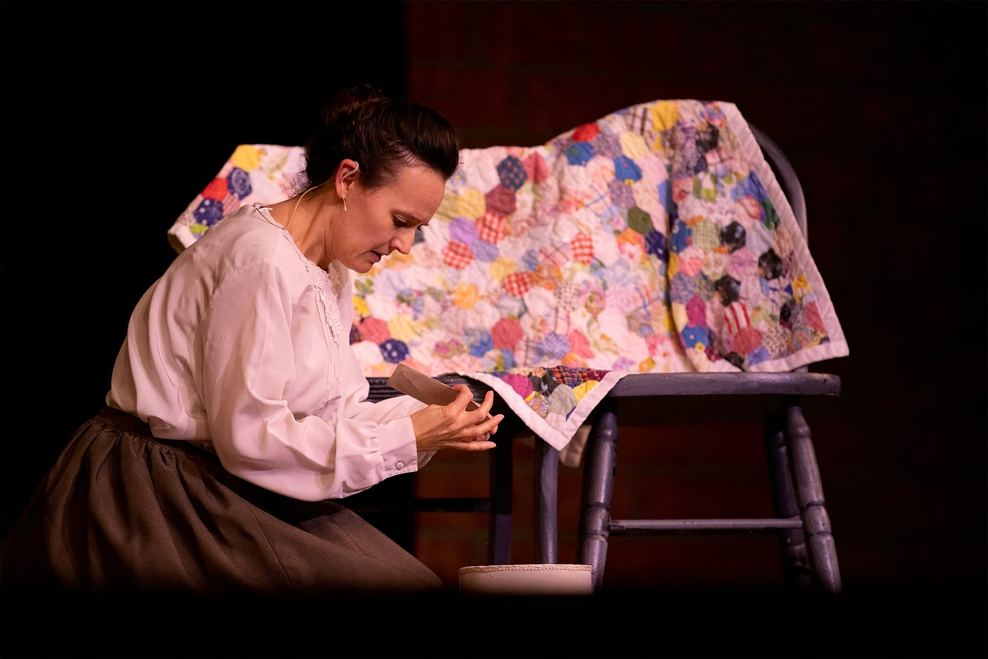 Woman in white blouse kneeling on the ground and looking at a letter. 