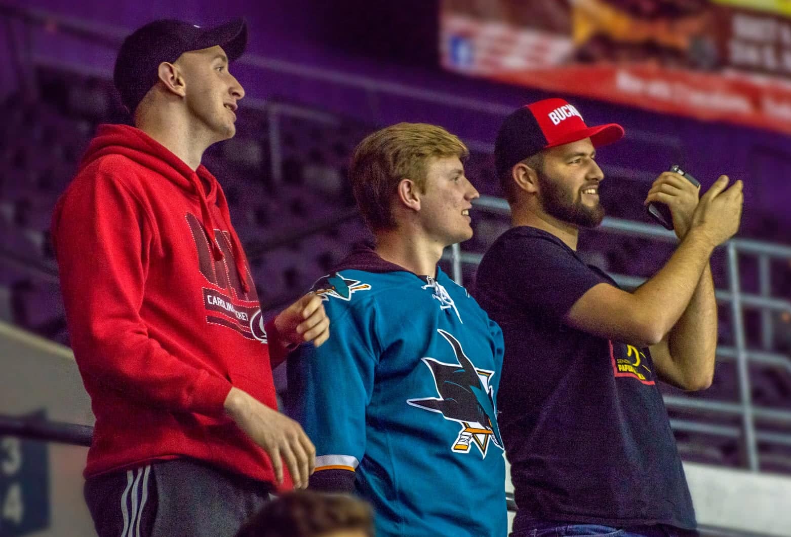 Three male students watching an Ice Flyers hockey game.