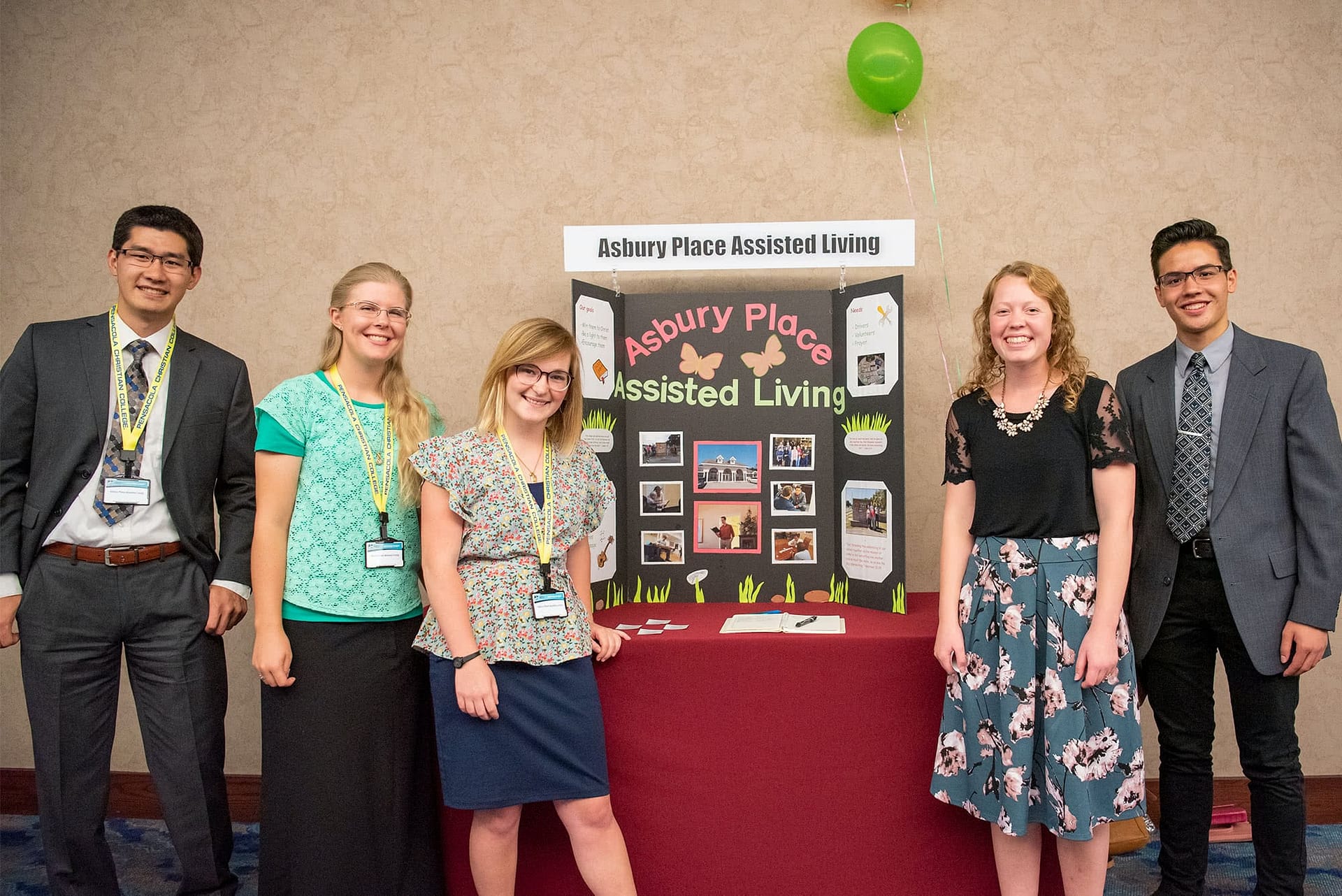 Five students pose with a poster about volunteering at Asbury Place Assisted Living