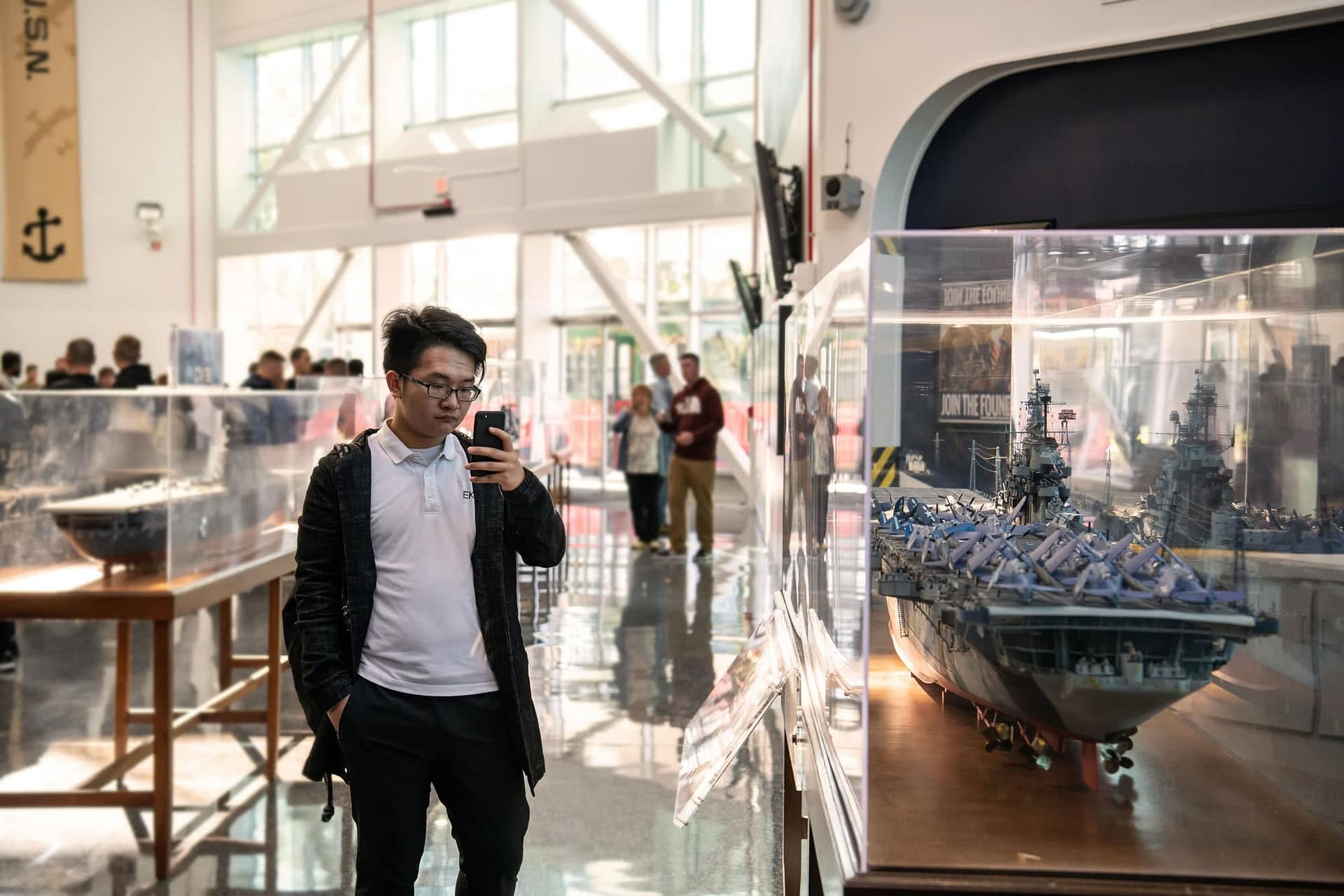 Male student taking a photo of a display at the Naval Aviation Museum.