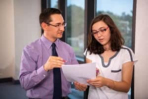 Mark Wainwright standing with a female student and looking at a paper. 