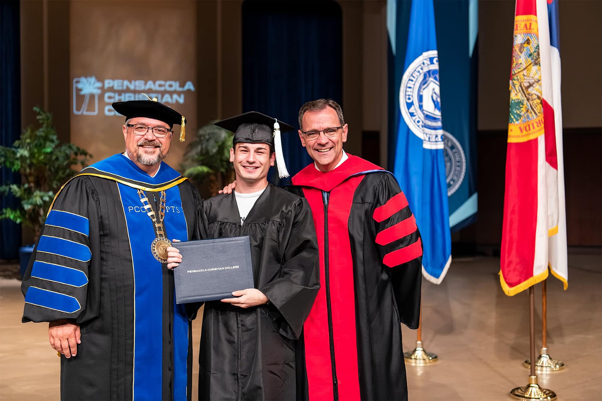Male PCC graduate standing with Dr. Shoemaker and Pastor Redlin.