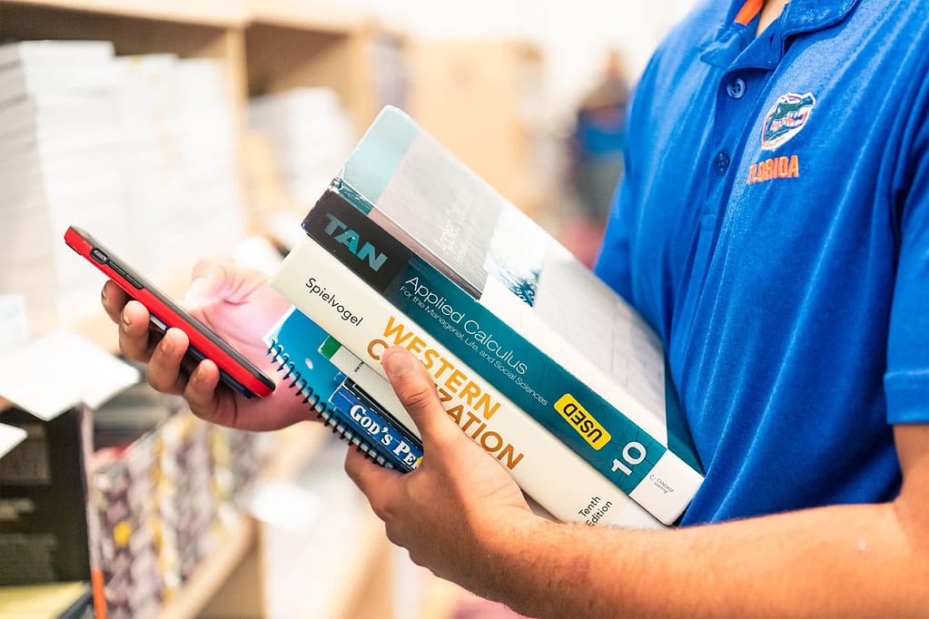 Student holding books and phone.