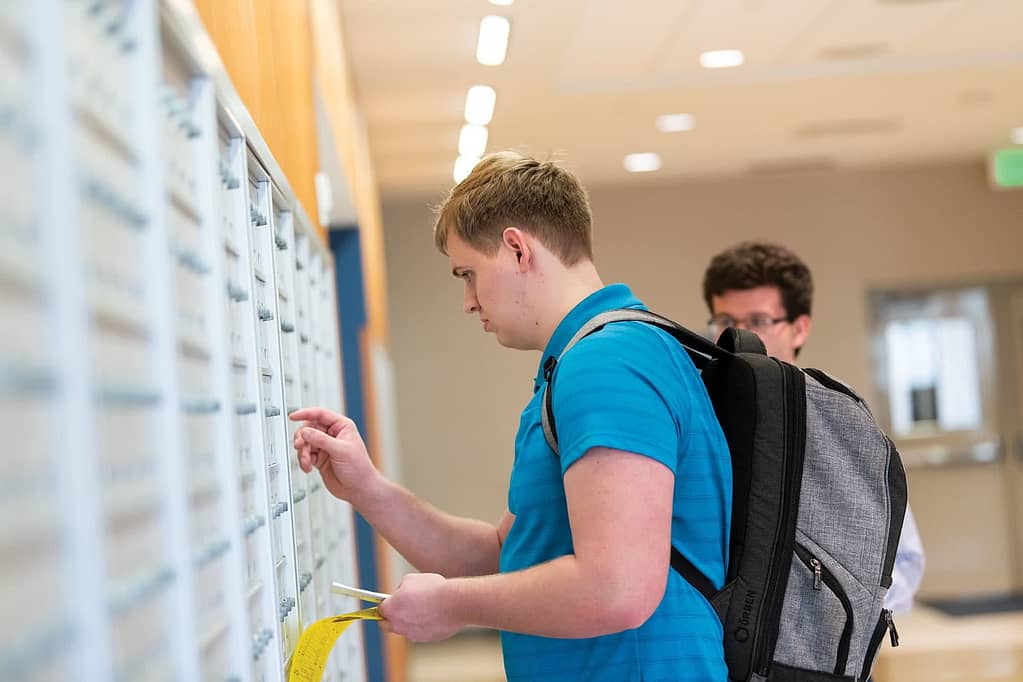 Male student opening his mailbox.