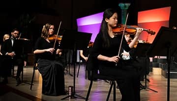 Students sitting and playing instruments.