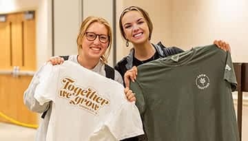 Two girls pose with their Growing Together shirts
