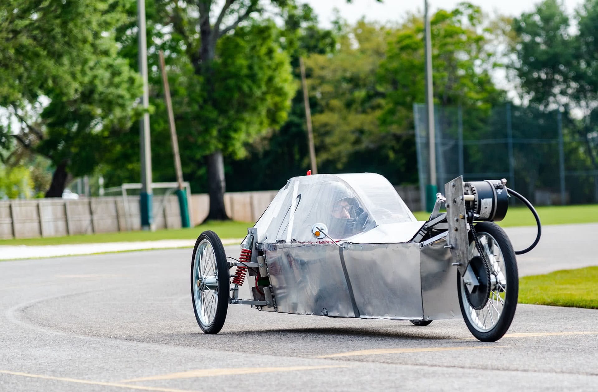 Student racing in a silver electric vehicle. 