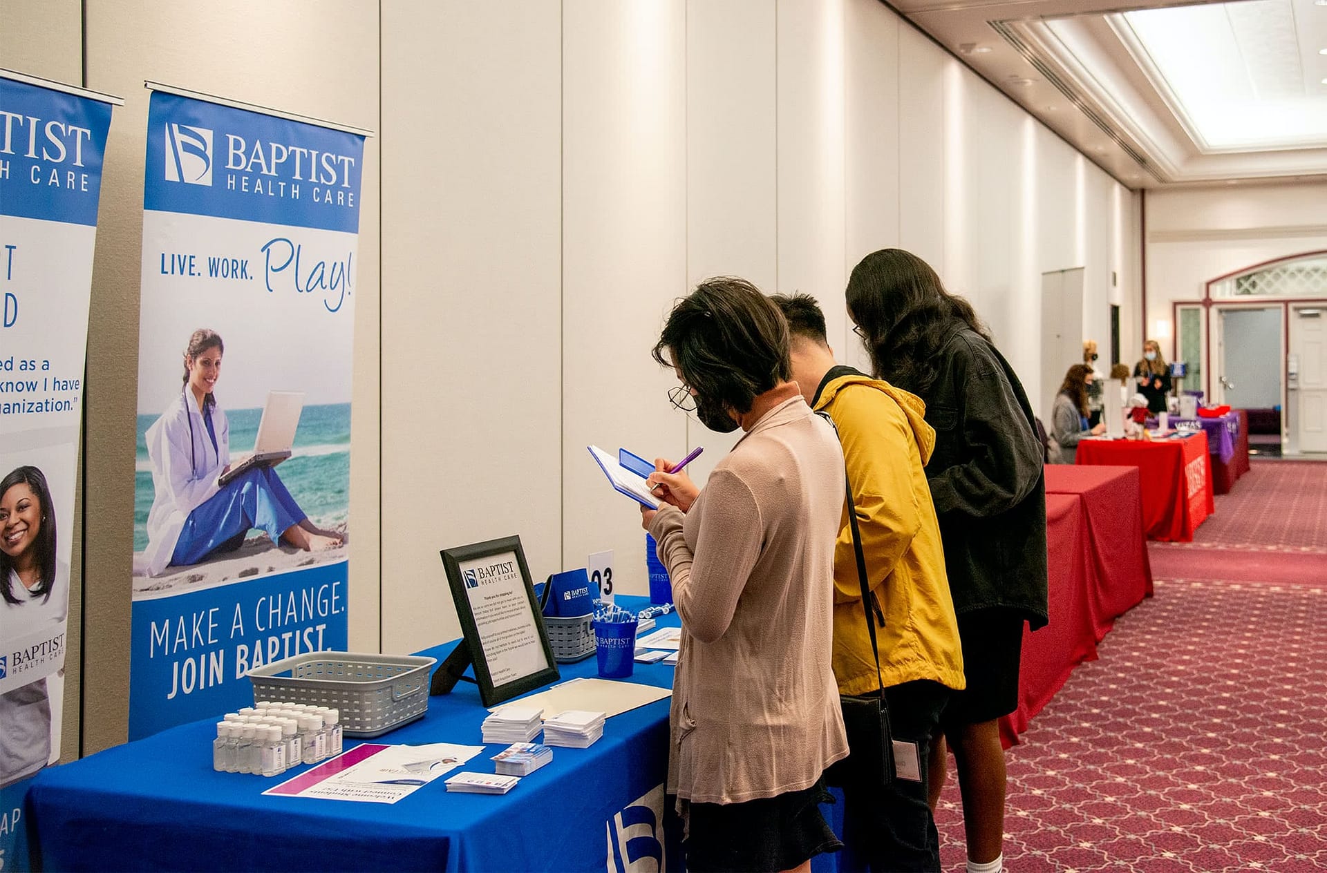 Three students standing at a healthcare booth at the Health Professions Career Fair. 