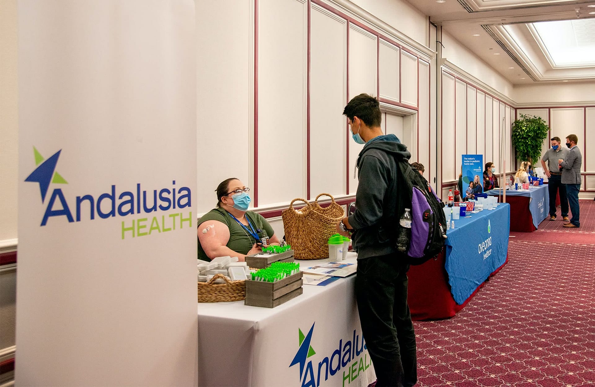 Male student speaking to a woman sitting behind a booth at the Health Professions Career Fair. 