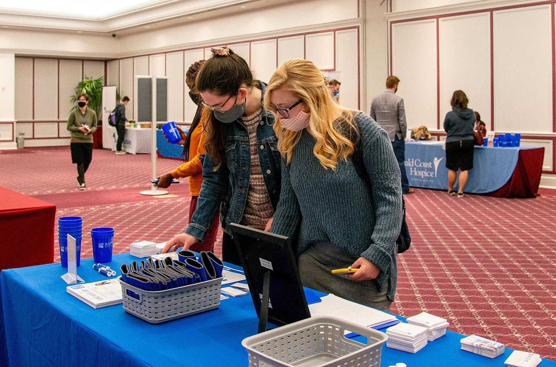 Two female students looking at information at a booth at the Health Professions Career Fair. 