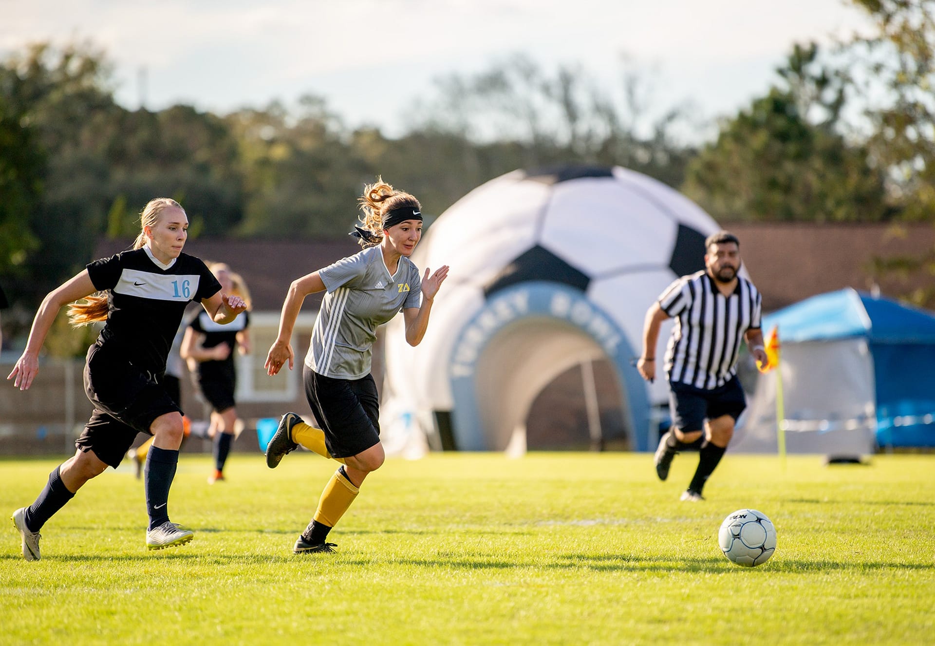 Female student soccer players running after the soccer ball on Eagle's Field. 