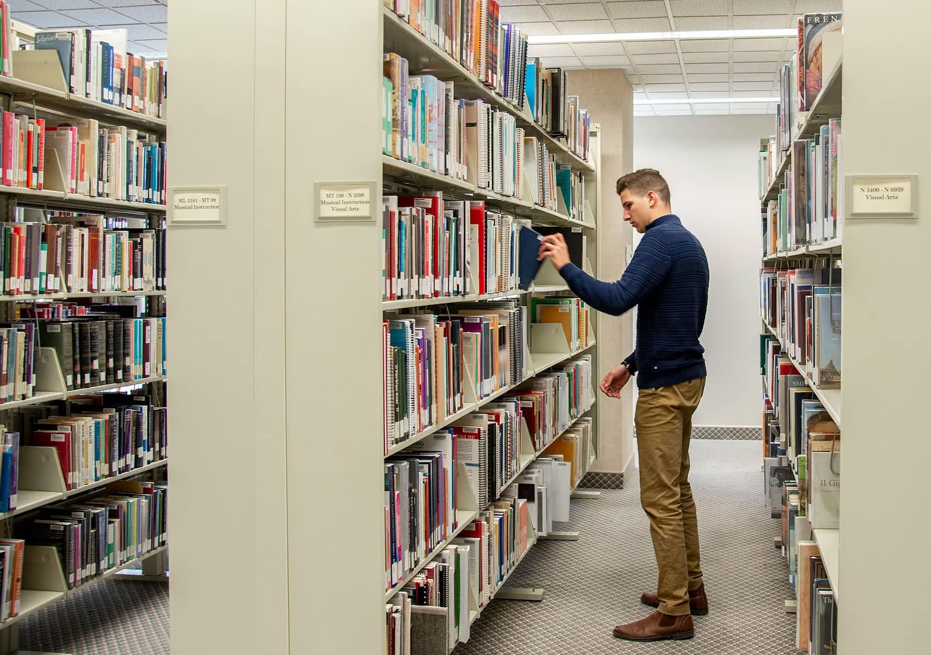 A male student picks out a book in the library