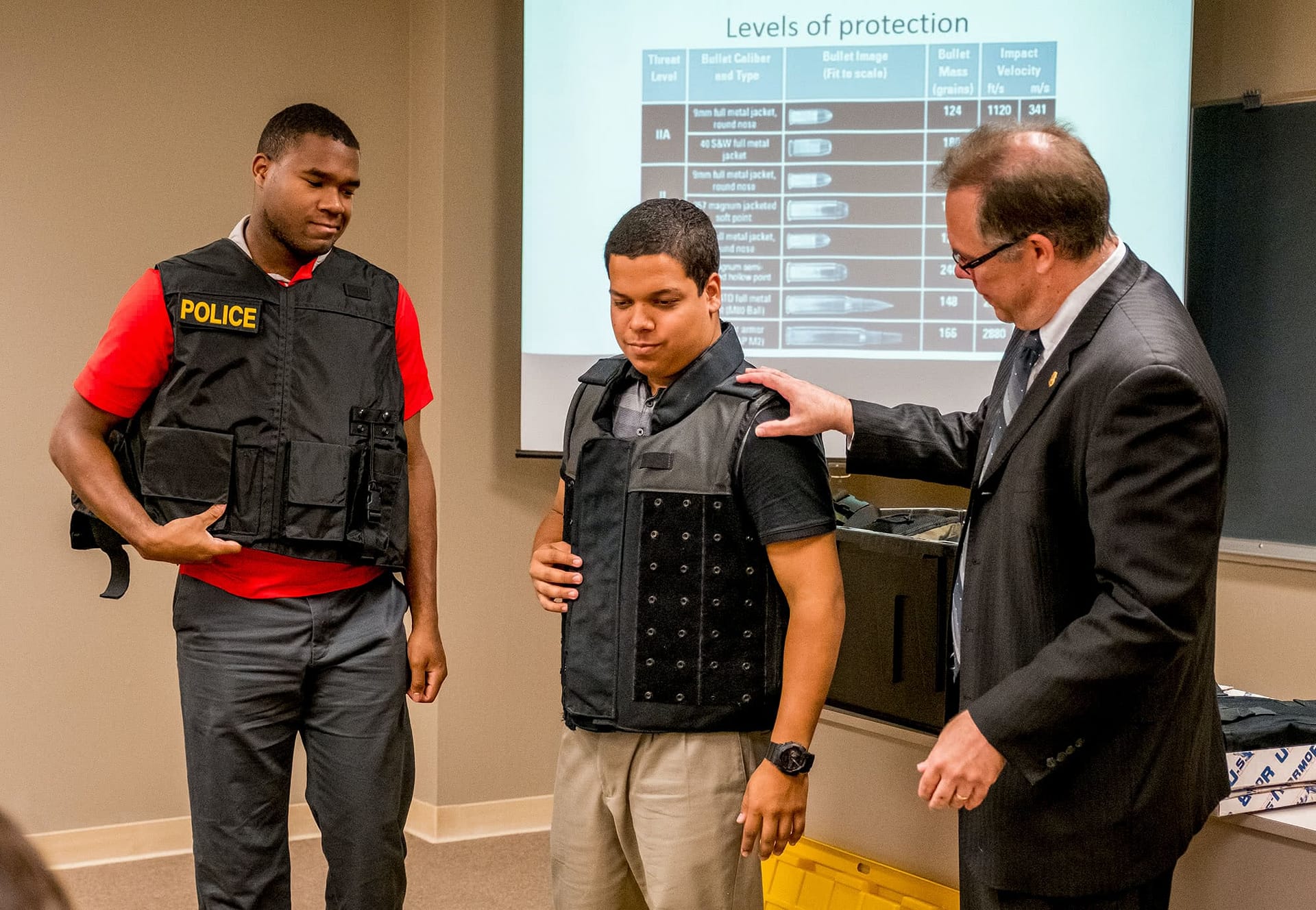 A male teacher shows his criminal justice class two bulletproof vests
