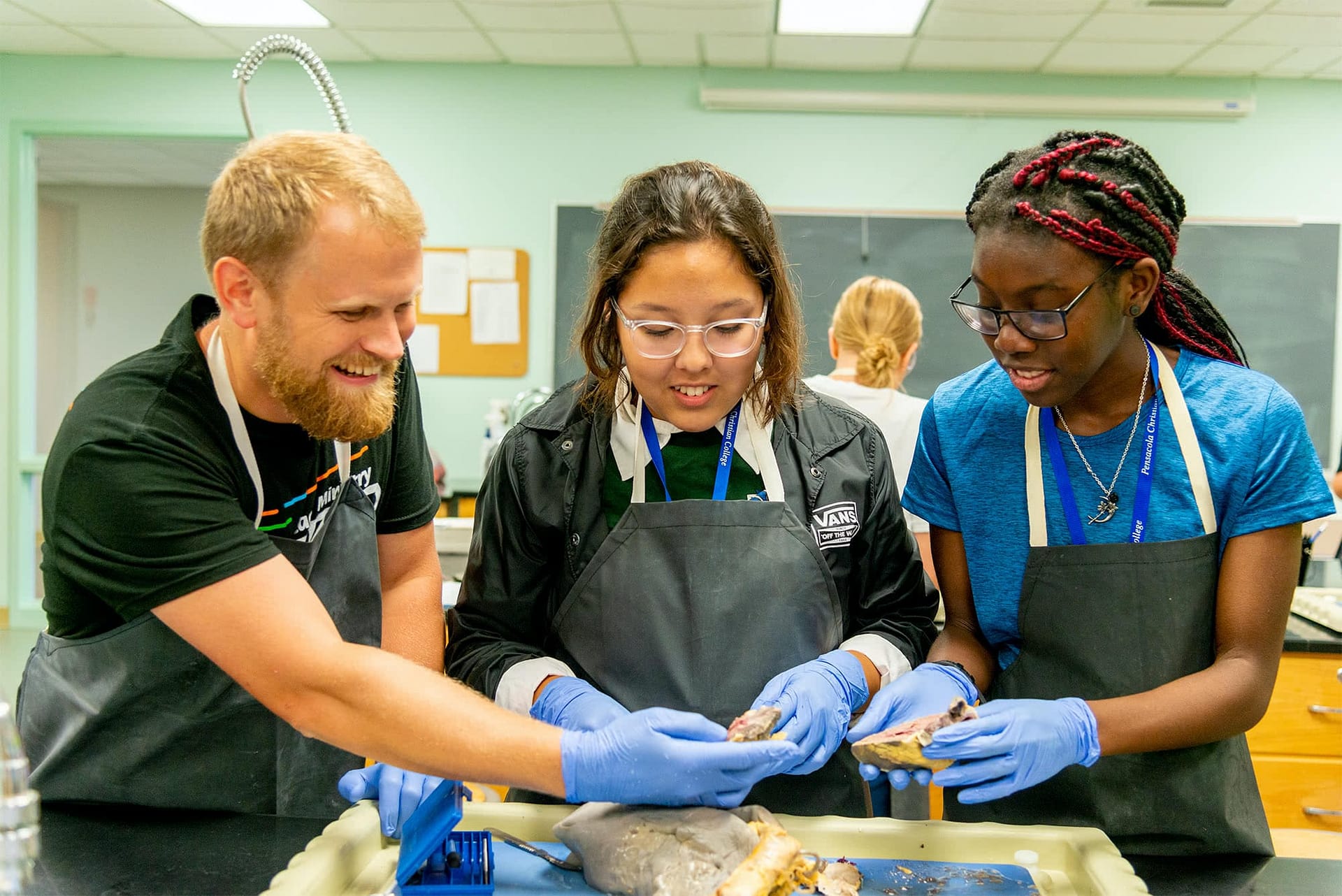 Dr. Spencer and two female academic campers dissecting an animal for pre-med camp. 