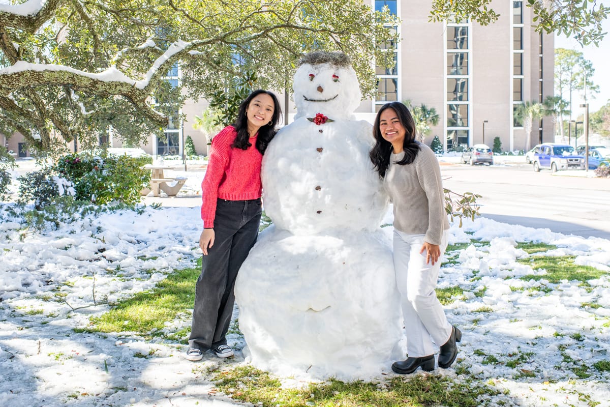 As the snow begins to melt, PCC students still enjoy the giant snowman under the oak tree.