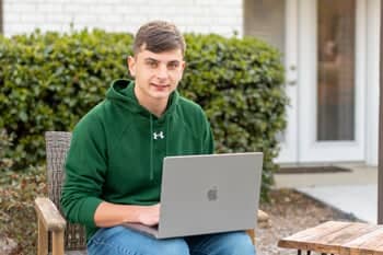 PCC Dual Enrollment student sits outside with his laptop