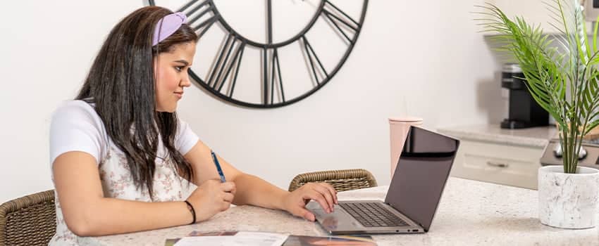 PCC Dual Enrollment student sits at her kitchen table working on her laptop