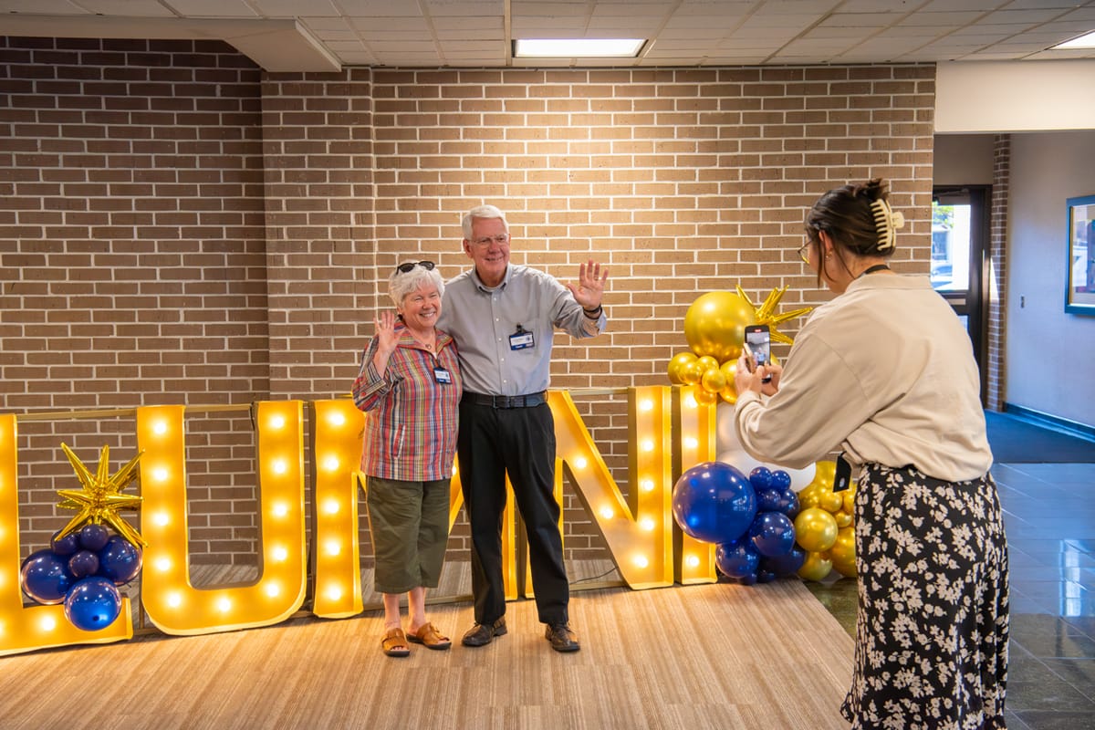 The Atkins posing in front of Alumni sign
