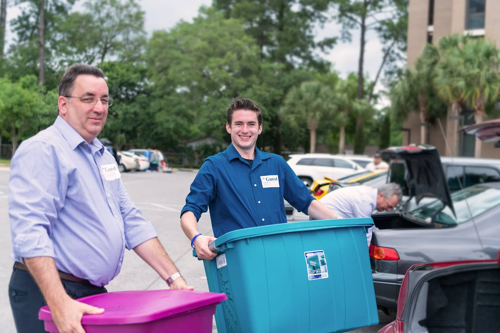 Two men move tubs from the dorm to the car