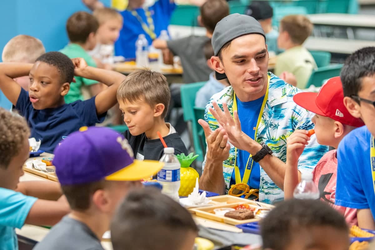 Sports Center Day Camp team leader talks with campers during their meal time