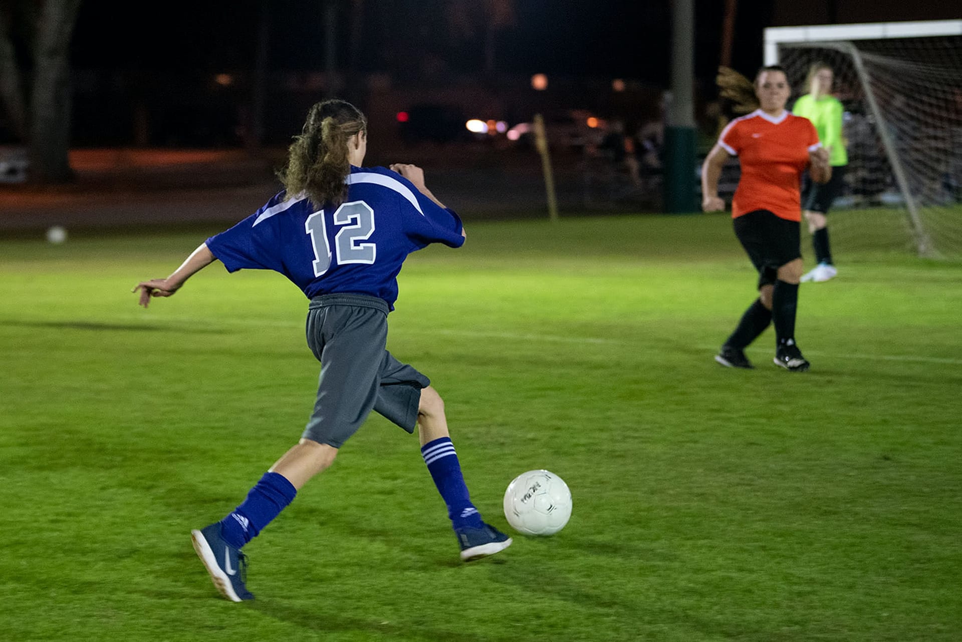 Women's collegian soccer player aiming to kick a soccer ball into the goal. 