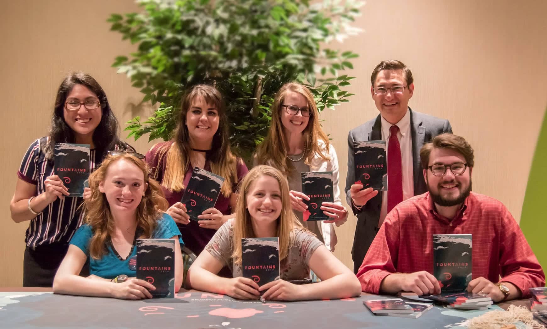 A group of people holding up copies of Fountains 2019. 