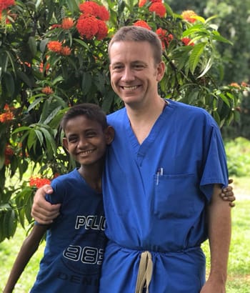 Alumni Dr. Brett Dempsey poses with little boy