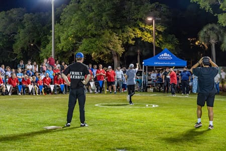 Someone pitching a wiffleball to a batter.