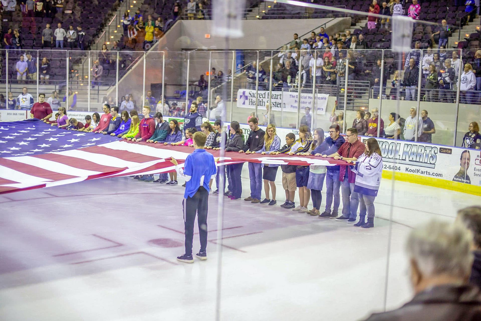 People holding the American flag over the ice. 